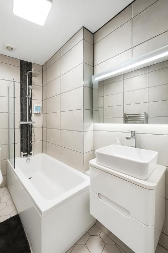 a white bathroom with a tub and a sink at The Fratton Apartment with parking in Portsmouth