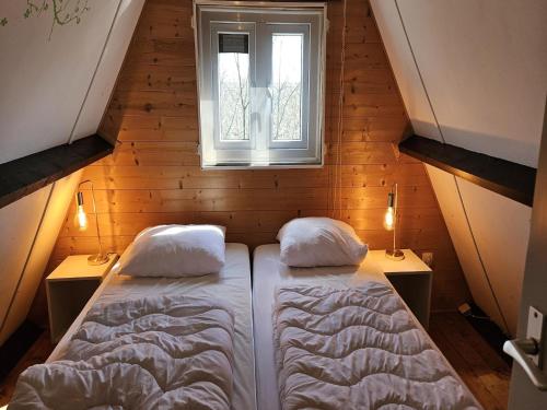 Una pequeña habitación con dos camas y una ventana. en Peaceful Forest Chalet near Durbuy, en Septon