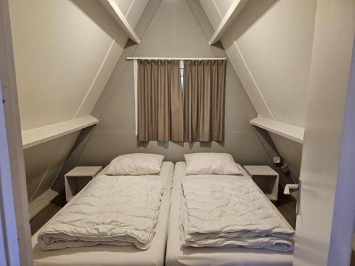 duas camas em um pequeno quarto com janela em Warm Countryside Haven in Durbuy em Septon