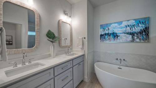 a bathroom with two sinks and two mirrors and a tub at Free Heated Pool Golf Cart Zone Sea La Vie by AvantStay in Port Aransas