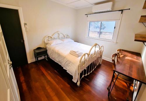 een slaapkamer met een wit bed en een raam bij Jarrah Cottage in Waroona