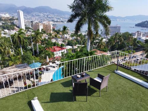 a balcony with a table and chairs on the grass at Casa Breizh in Acapulco