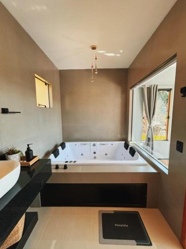 a large bathroom with a tub and a sink at Recanto do Tabuleiro chalé com hidro, lareira, churrasqueira e cozinha perto de floripa in Aguas Mornas