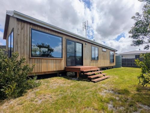 Sisters Beach Hideaway - A Coastal Escape في Sisters Beach: منزل خشبي مع طاولة نزهة في ساحة