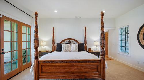 a bedroom with a wooden four poster bed and windows at Wellsona Vineyard Retreat Pool Hot Tub Views Main Home Guest Home in Paso Robles