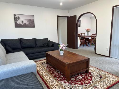 a living room with a couch and a coffee table at Carnoustie Calm- A Cosy Wattle Downs Home in Auckland