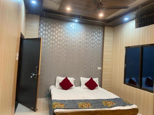 a bedroom with a bed with two red pillows at Hotel Aurihar jn in Saidpur
