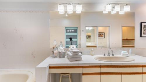 a bathroom with a sink and a tub and a mirror at Oceanfront w Game Room Fire Pit Panoramic Views Angels Landing by AvantStay in Langley