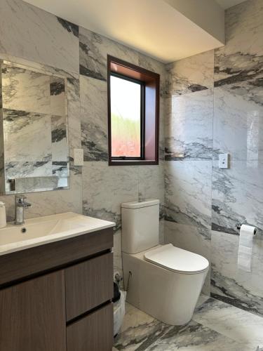 a bathroom with a toilet and a sink and a window at Carnoustie Calm- A Cosy Wattle Downs Home in Auckland