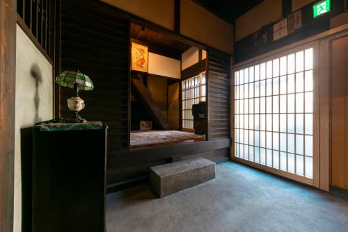 アトレチア祇園宇治別邸プレミアム في يوجي: غرفة بسرير ومقعد ونافذة