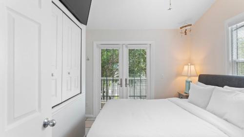 Coral Breeze by AvantStay Close to Beach w Balcony Shared Pool Month Long Stays Only في ستوك آيلاند: غرفة نوم بيضاء مع سرير ونافذة