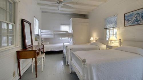 Un dormitorio con cuatro camas y un escritorio con cómoda. en 1111 Middle Street by AvantStay Charming Historic Cottage Featured in Dear John Movie Beach Access, en Sullivans Island