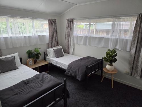 a bedroom with two beds and two windows at Accessible Respite House in Whangarei