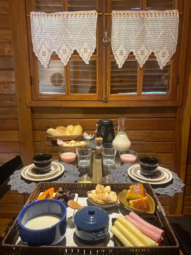 einen Tisch mit Teller und Schalen mit Lebensmitteln in der Unterkunft Sítio Reichart - Andorinhas Atlantic Forest Retreat in Marechal Floriano