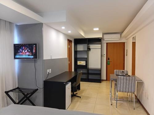 フェイラ・デ・サンタナにあるSuítes Executivasの机と壁にテレビが掛かっている部屋