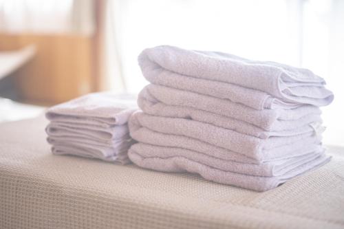 a stack of towels sitting on top of a bed at よんなーハウス in Kameoka