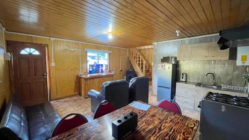 Una cocina con mesa y sillas y un refrigerador. en Cabaña la percha II, en Coyhaique