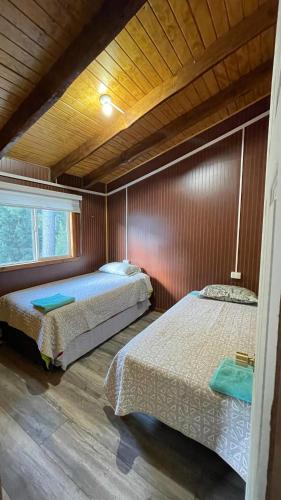 Un dormitorio con dos camas y una ventana. en Cabaña la percha II, en Coyhaique
