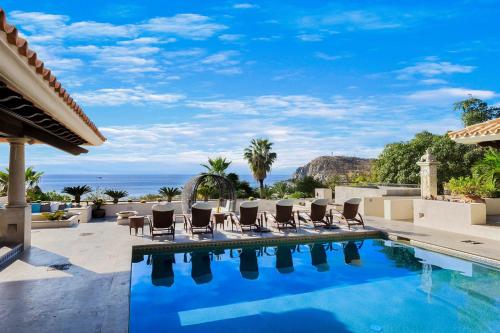 a pool with chairs and the ocean in the background at Casa Brooks in Cabo San Lucas