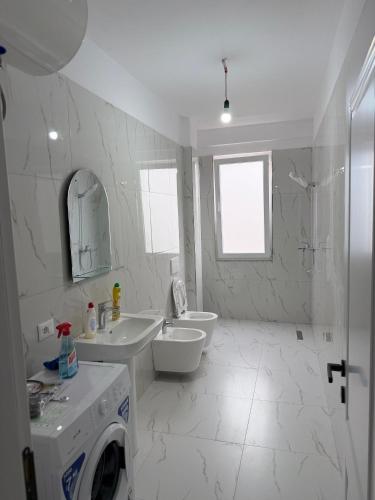 Modern 2-Bed Near Tirana and Airport with Balconies في Kamëz: حمام ابيض مع مغسلة وغسالة ملابس