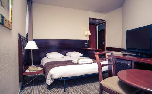a hotel room with two beds and a desk and a television at Mercure Port La Grande Motte in La Grande-Motte