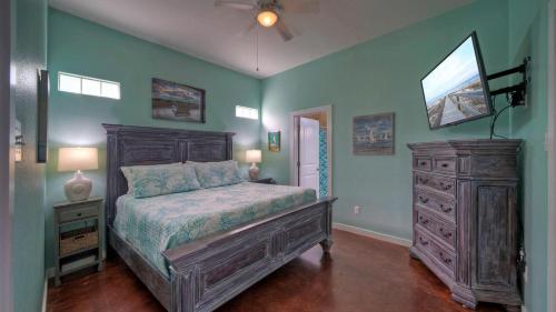 a bedroom with a bed and a dresser with a television at Shared Resort-Style Pool Playground Patio w Bar Tidal Times by AvantStay in Port Aransas