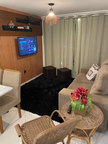 a living room with a couch and a table with flowers on it at Mar e sol residencial 2 quartos com ar condicionado,500 metros da praia de Jacumã in Conde