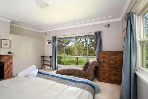 a bedroom with a bed and a chair and a window at The Nineteenth in Blackheath