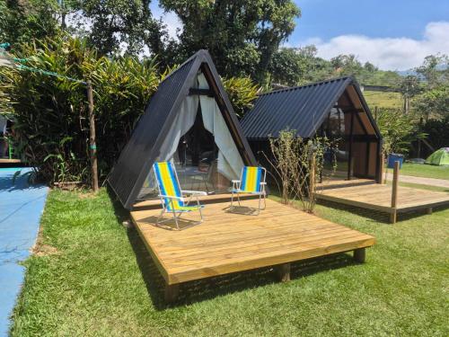 a tent with chairs on a deck next to a pool at Camping & Cabanas Ilhabela in Ilhabela