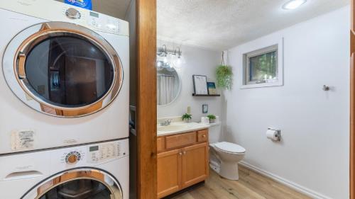 Lakeshore Oasis by AvantStay Private Beach Views Hot Tub Volleyball في Blakeslee: حمام مع غسالة ومجفف بجانب حوض