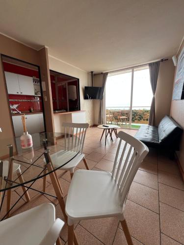 Departamento frente al mar في تومي: غرفة معيشة مع طاولة زجاجية وكراسي بيضاء