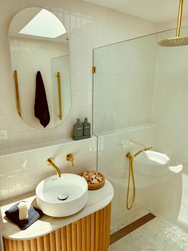 a bathroom with a sink and a mirror and a tub at Barbara's Beach House in Hallidays Point