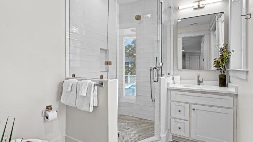 a white bathroom with a shower and a sink at All Decked Out Seagrove by AvantStay Priv PoolHot Tub Ocean Views in Santa Rosa Beach