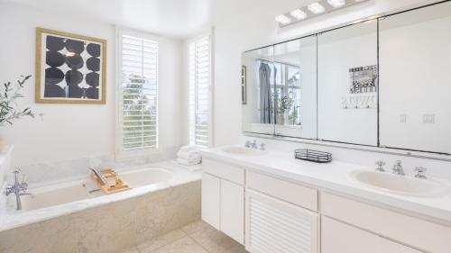 a white bathroom with two sinks and a tub and a tubermott at Stardust by AvantStay Views Hot Tub Pool Table in Malibu