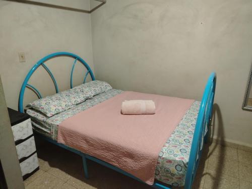 Dormitorio pequeño con cama azul y toalla en Hospedaje carvajal, en David
