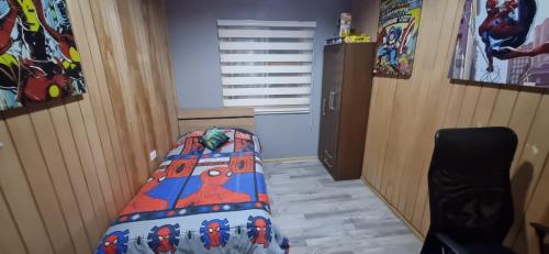 a bedroom with a bed with a comforter on it at Casa mirador de volcanes, 6 personas in Llanquihue