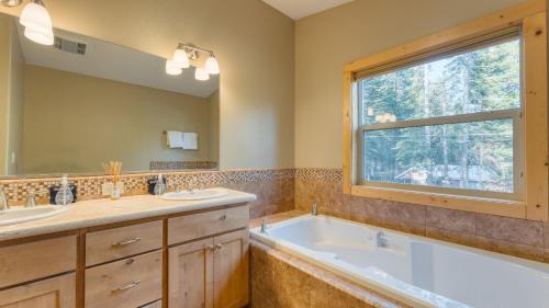 a bathroom with two sinks and a tub and a window at Washoe Chalet by AvantStay Game Room Hot Tub Putting Green Fire Pit in Tahoma