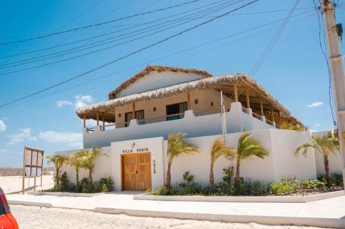 a house on the beach with palm trees at Villa Vento in Camocim