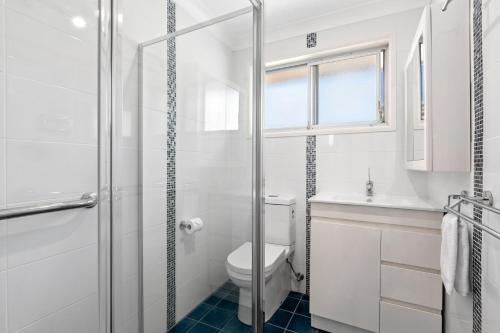 een witte badkamer met een toilet en een wastafel bij Ziggy's Place in Gerringong