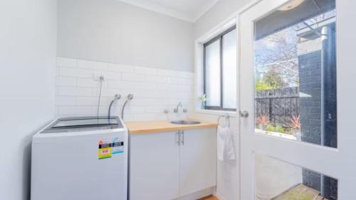 EpsomNouveau Home的带水槽和窗户的白色厨房