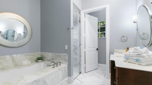 a bathroom with a tub and a sink and a mirror at Marco Polo by AvantStay Waterfront 5BDR Pool Spa Fire Pit Walk to Beach in Marco Island