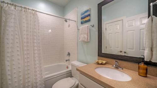 Un baño con lavabo, inodoro y espejo. en Chic 2BR Coastal Condo Shared Pool Near the Beach Costa Bahia 103, en Port Aransas