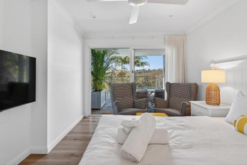 Un dormitorio blanco con una cama y una sala de estar. en Garigal Studio 1br Unit with Pool Access, en Forestville