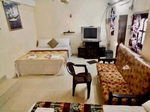 コロンボにあるManimalar guestのベッド2台、テレビ、ソファが備わる客室です。