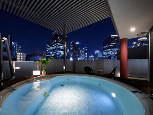 Minn Umeda North في أوساكا: حوض استحمام ساخن على سطح مبنى مع أفق المدينة