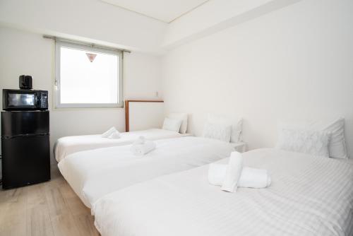 two white beds in a room with a window at StayKobeC in Kobe