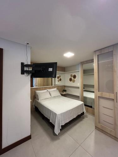 a bedroom with a bed and a flat screen tv at Residence Farol - Loft 213 - Vista mar Prainha e Farol in Laguna