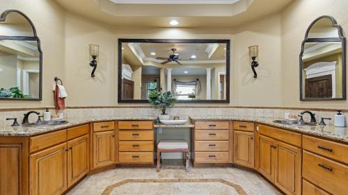 a bathroom with two sinks and two mirrors at Hilltop Estate w Pool Hot Tub Fire Pit Views Cleveland Vista by AvantStay in Murrieta