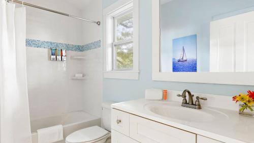 ein weißes Badezimmer mit einem Waschbecken, einem WC und einem Fenster in der Unterkunft Beach Bungalow 1blck to Beach w Hot Tub Game Room Haven Grove by AvantStay in St. Augustine