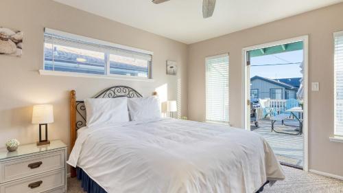 a bedroom with a white bed and a balcony at Steps to Beach w PatioDeck Foosball Happy Bottom Beach House by AvantStay in Oceano